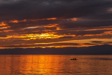 Two unrecognizable people paddling on the lake at golden hour. Sport concept