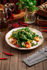 Gourmet shrimp salad with avocado and arugula on wooden background