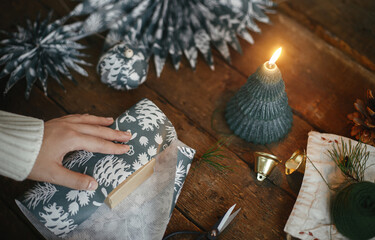 Wrapping christmas gift. Hands wrapping simple gift box in festive blue paper on rustic wooden...