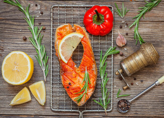 Delicious salmon steak grilled with lemon and pepper on a black plate. Top view