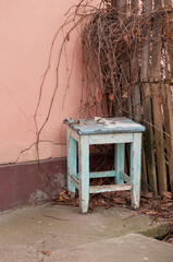 an old wooden blue stool on a pink wall background
