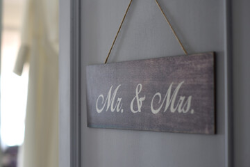 Wooden wedding day sign with Mr & Mrs; bride's dress in background