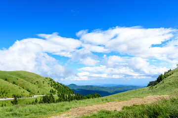 Scenic view over Bucegi Mountains (Muntii Bucegi) in Romania in a sunny summer day with clear blue sky and white clouds.