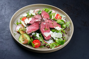 Modern style traditional fried dry aged bison beef rump steak slices with vegetable, lettuce and...