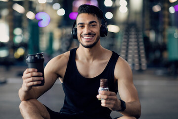 Fitness Nutrition. Happy Muscular Arab Man Holding Sport Shaker And Protein Bar