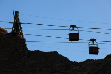 Silhouette of an old cable car and two trolleys for coal mining, at sunset, against a sky. Energy...