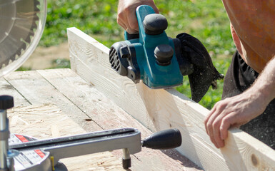 a worker processes a board with an electric plane