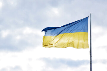 Large national flag of Ukraine flies in the blue sky. Big yellow blue Ukrainian state banner in the Kharkiv city.