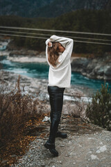 Young woman in mountains river and autumn forest; traveller in beautiful nature. Siberian nature - Altai mountains and turquoise Katun in autumn cloudy evening