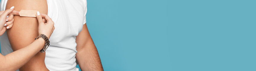 Young european nurse apply plaster on shoulder of mature male after vaccination