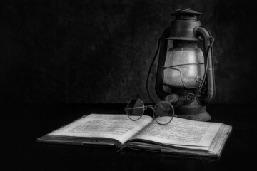 Black and White Studio Still Life Image of an Antique Lantern, Antique Book and Antique Spectacles 