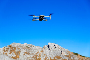 Fototapeta na wymiar Drone flying over the mountains. Modern compact drone with a camera. 