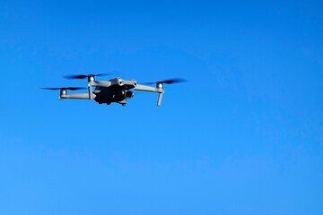 Drone flying in the blue sky. Modern compact drone.