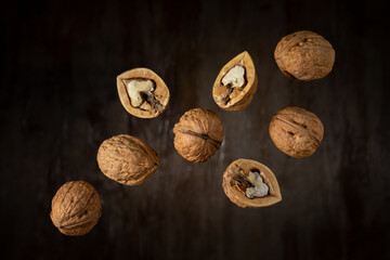 flying dried walnuts against a dark brown woody soft backdrop