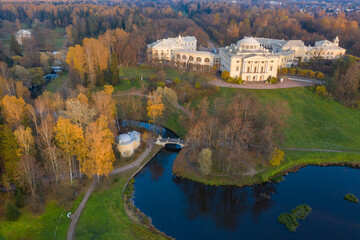 Fototapeta premium Panoramic aerial view of the Pavlovsk Park and the Pavlovsk Palace on an autumn evening.Bright autumn landscape, Slavyanka river,centaur bridge. A suburb of St. Petersburg.