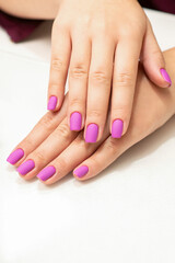 Obraz na płótnie Canvas Beautiful fingers with purple nails after nail polish procedure in manicure salon