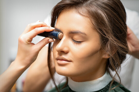 Make up artist contouring the face of a young woman with cream blush close up