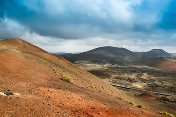 Volcanic landscape in Timanfaya National Park on Lanzarote, Canary Islands, Spain. Dramatic views of volcano craters and desert with black and red lava, ash. Lunar or martian surface