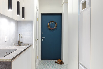 A minimalistic interior of a hallway in a studio apartment in white and gray shades with a blue...