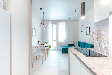 Minimalistic interior design studio apartment with white walls and a turquoise green sofa. Living room and dining room for a comfortable life