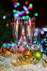 glasses with a drink champagne wine with a decor of Christmas toys on a bokeh background for the new year