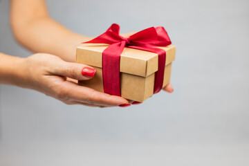 girl holding a surprise gift box with a red bow and ribbon in her hands for the holiday valentine's and new year's birthday