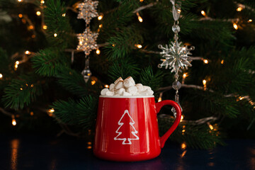 christmas hot chocolate with marshmallows in a red mug with a garland on the background.Christmas and new year. Winter holidays