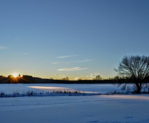 Letzte Sonnenstrahlen fallen auf schneebedeckte Landschaft.