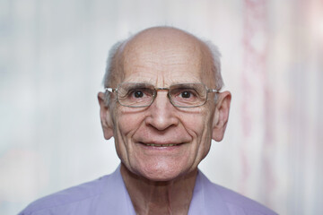 Older man in eyewear smiling with teeth and looking at camera