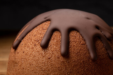 French mousse cake covered with chocolate glaze on wooden background.