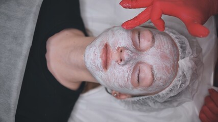 Application of a cream mask on the face of a girl with problem skin in the salon.