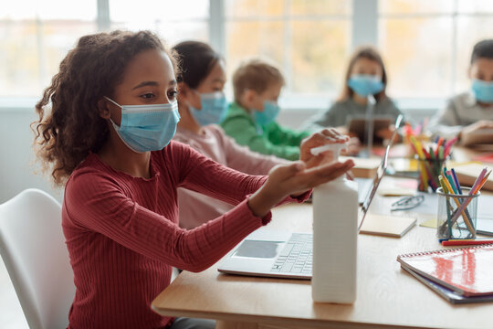 Black Schoolgirl Disinfecting Hands Wearing Face Mask At School
