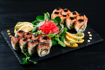 Rice square rolls with shrimp, eel, vegetables, creamy white cheese and sweet sauce. Asian sushi of two types on tray