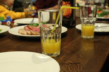 a glass of orange apricot yellow juice in a glass with a straw stands near a plate in the cafe's restran. Lunch at the cafe restaurant outside the house