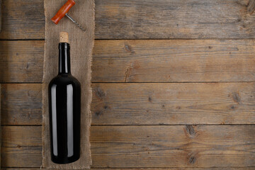 Close up of red wine bottle with stopper and corkscrew on natural wooden table background with copy space