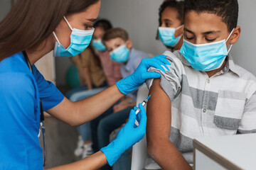 Medical Worker Making Vaccine Injection Vaccinating African American Boy Indoors