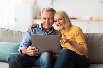 Happy Senior Couple Using Laptop Browsing Internet Together At Home