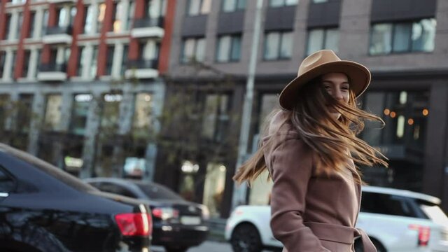 Happy long hair woman in a coat and hat turn around and look at camera