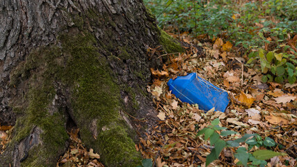 An old blue plastic canister from gasoline lies in the forest among the leaves. Environmental...