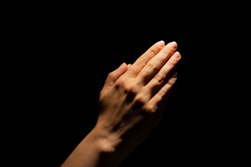 Fototapeta premium Praying hands on a black background. Light from above. Hands folded in prayer. Hand gestures