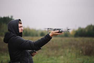 Man holding drone and remote control against field background