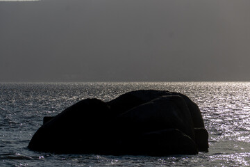 stone on the calm waters of the sea in the afternoon of sunset