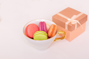 Sweet dessert, macaroons in mug and gift box on white background