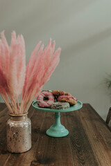 still life with pink bunny tail boho plants and donuts 