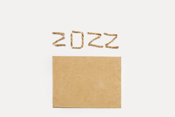Blank eco card. Happy New year 2022. New Year Concept welcoming New Year 2022 written by craft rope or jute on white background. Two thousand twenty two. Eco holiday. Copy space. Simple greeting