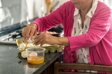 Latin Grandma breaking eggs for breakfast at her kitchen