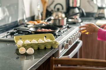 Two egg shells next to the egg pack near the stove at the kitchen