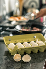 Close up of two egg shells next to the egg pack near the stove