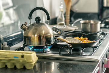 Close up of the stove cooking food and boiling water in a teapot