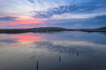 Soft and peaceful sunrise aerial waterscape with clouds and reflections